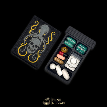 Kraken's Whisper art edition pill organizer: anthracite kraken wrapped around the skull, gold suckers, on matte black, beside a filled 5-compartment base.