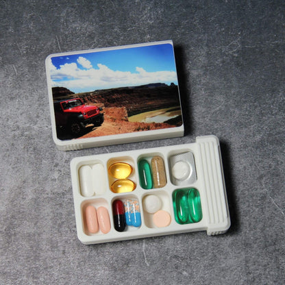 Custom photo pill organizer, white, lid removed: 8-compartment base in two rows, each cell holding tablets, capsules or softgels