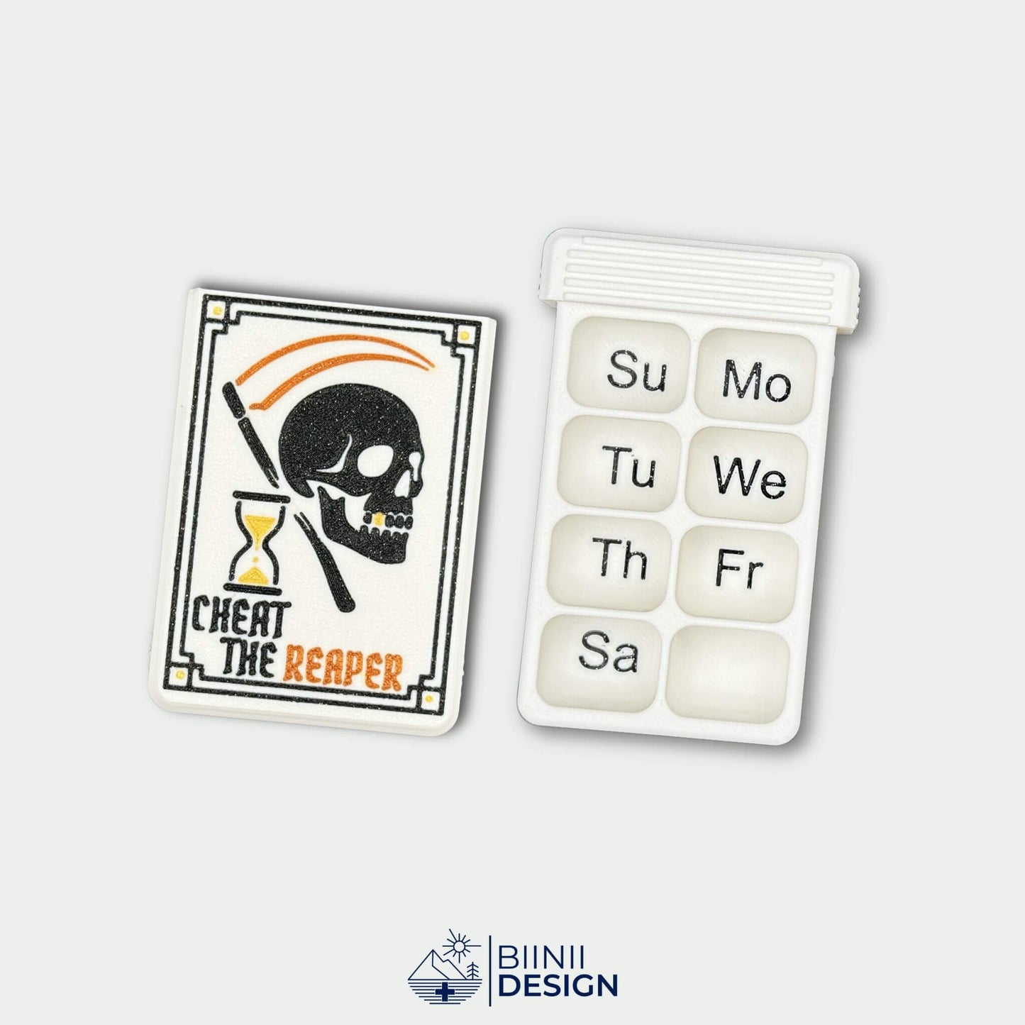 Cheat the Reaper White Edition lid beside white 8-compartment weekly tray with black English Sunday start engraving.