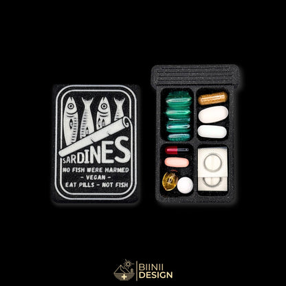 Sardines art edition pill organizer lid beside its 4-compartment base filled with assorted supplements, sardine tin artwork.