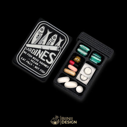 Sardines art edition pill organizer: silver sardine tin artwork on galaxy black, beside a filled 5-compartment base.
