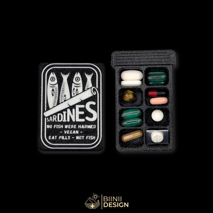 Sardines art edition pill organizer lid beside a filled 8-compartment base holding tablets, capsules and supplements.