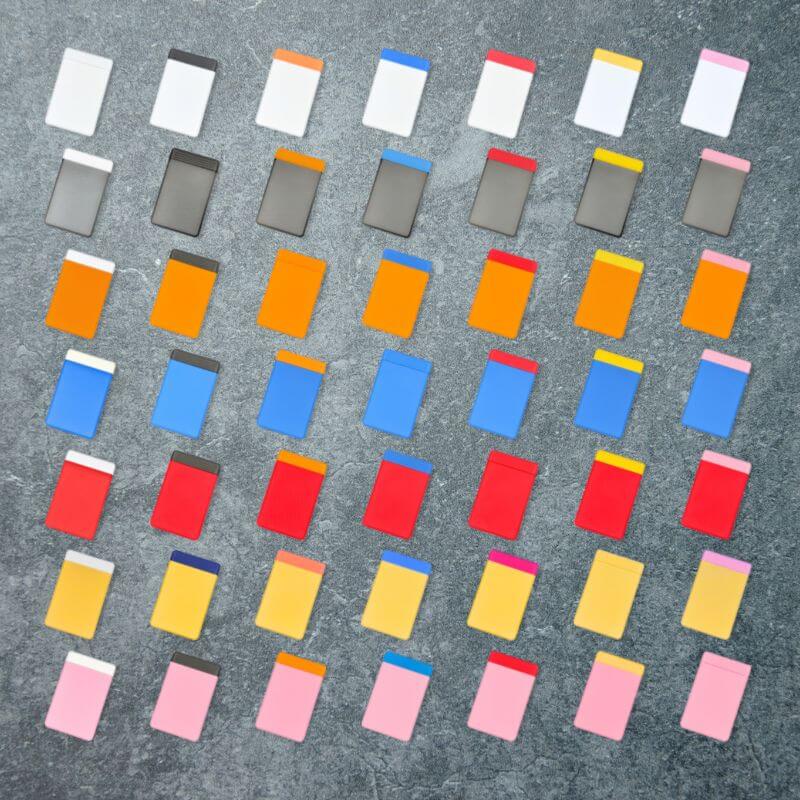 The 49 color combinations of the travel pill organizer, seven lid colors by seven base colors, laid out in a grid on slate.