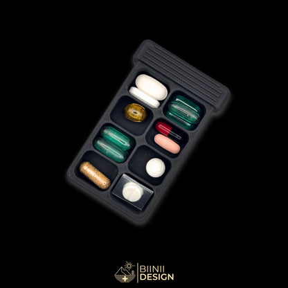 8-compartment base of the Vulture's Shadow art edition pill organizer, filled with tablets, capsules and supplements of varied sizes.