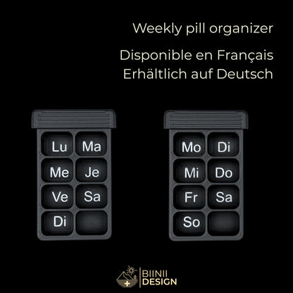 Two empty weekly bases of the Vulture's Shadow art edition pill organizer, French and German days printed in the same silk silver as the artwork.